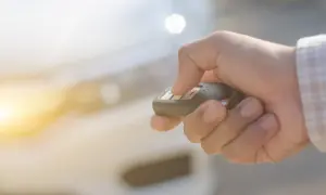 Dłoń trzymająca kluczyk samochodowy z widocznymi przyciskami.