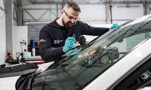 Fachowiec z Autoglass naprawia pęknięcie na szybie. Sprawdź autoglass cennik usług.