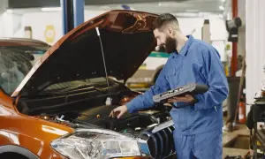 Mechanik z komputerem diagnostycznym sprawdza silnik. Szybko dowiedz się, ile trwa wymiana oleju w Twoim aucie.
