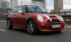 Czerwony Mini R50 z białymi pasami pędzi po moście, w tle nowoczesne budynki i Pałac Kultury.