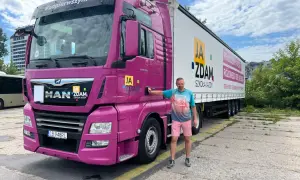 Mężczyzna obok różowej ciężarówki MAN. Na naczepie napis "JA ZDAM SZKOŁA JAZDY". Całkowity koszt prawa jazdy kat C+E do ustalenia w szkole.