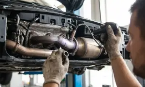 Mechanik naprawia układ wydechowy Renault, prawdopodobnie z powodu błędu dtc p0420.