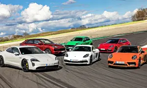 Kolekcja sportowych modeli Porsche: biały Taycan, czerwony Cayenne, zielony Macan, biały Cayman, czerwona Panamera Sport Turismo i pomarańczowy 911 na torze wyścigowym.
