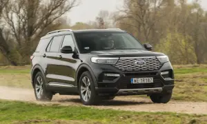 Czarny Ford Explorer 4x4 pokonuje piaszczystą drogę wśród jesiennej przyrody.