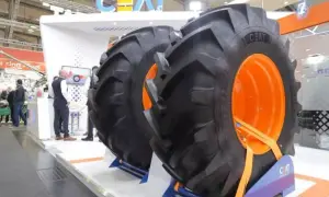 Dwa ogromne opony CEAT z pomarańczowymi felgami na stoisku targowym.