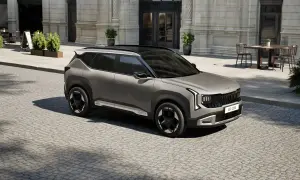 Nowoczesne kia modele, jak ten szary SUV, prezentują się stylowo na brukowanej ulicy przed kawiarnią.