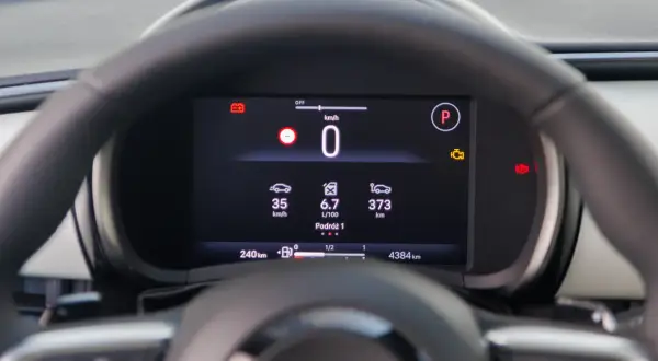 Cyfrowy kokpit pokazuje prędkość 0 km/h, średnie spalanie 6.7 L/100km i dystans 373 km. To pomocne informacje, jak obliczyć spalanie.