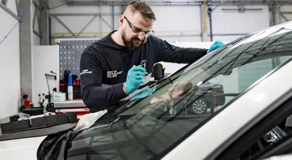 Fachowiec z Autoglass naprawia pęknięcie na szybie. Sprawdź autoglass cennik usług.