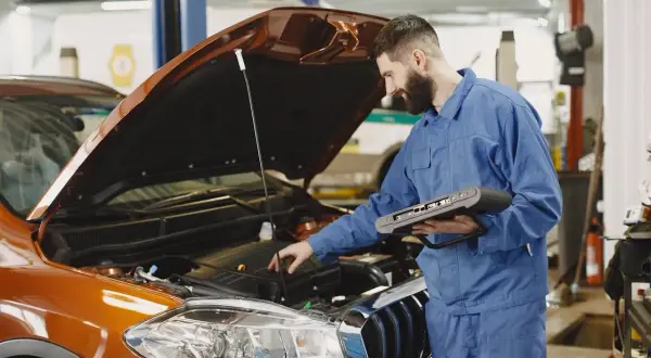 Mechanik z komputerem diagnostycznym sprawdza silnik. Szybko dowiedz się, ile trwa wymiana oleju w Twoim aucie.