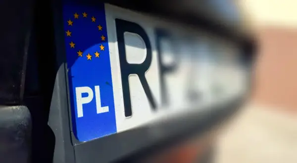 Zbliżenie na polską tablicę rejestracyjną z symbolem UE. Litery "PL" i fragment numeru rejestracyjnego są wyraźne.
