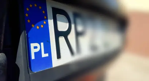 Zbliżenie na polską tablicę rejestracyjną z symbolem Unii Europejskiej. Litery "PL" i fragment numeru wskazują na rkl rejestracja.