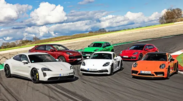 Kolekcja sportowych modeli Porsche: biały Taycan, czerwony Cayenne, zielony Macan, biały Cayman, czerwona Panamera Sport Turismo i pomarańczowy 911 na torze wyścigowym.