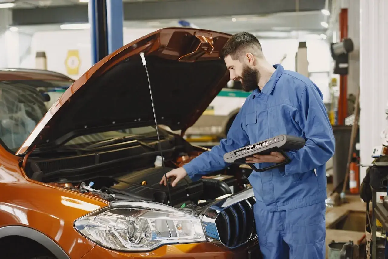 Mechanik z komputerem diagnostycznym sprawdza silnik. Szybko dowiedz się, ile trwa wymiana oleju w Twoim aucie.