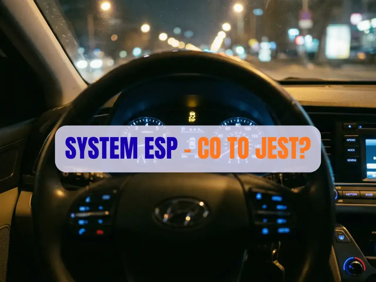 Wnętrze samochodu nocą, widok na kierownicę i deskę rozdzielczą. Na ekranie świeci się kontrolka "SYSTEM ESP - CO TO JEST?".