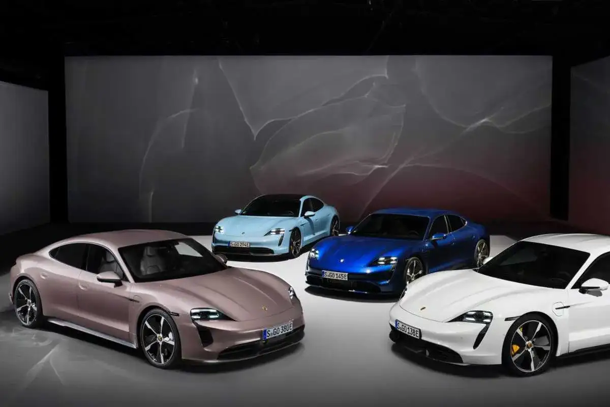 Cztery elektryczne Porsche Taycan w różnych kolorach: różowym, jasnoniebieskim, niebieskim i białym, prezentowane na tle abstrakcyjnej grafiki.
