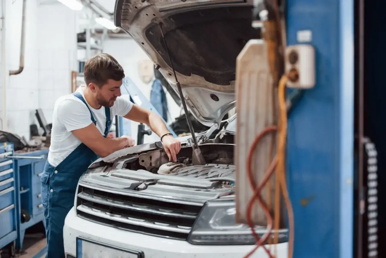 Mechanik w warsztacie samochodowym pracuje nad silnikiem. Każda roboczogodzina jest cenna, by auto znów sprawnie jeździło.