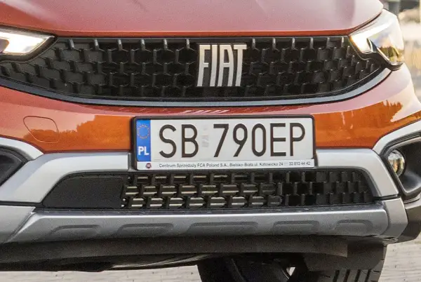Pomarańczowy Fiat z tablicą rejestracyjną SB 790EP. Detale przedniego grilla i logo marki.