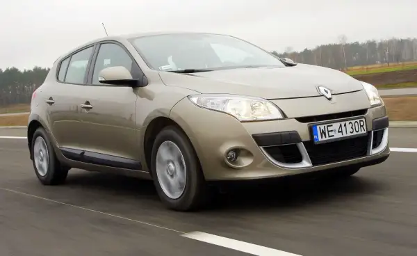 Złoty Megane 3 w ruchu drogowym, z widocznym numerem rejestracyjnym WE 4130R.