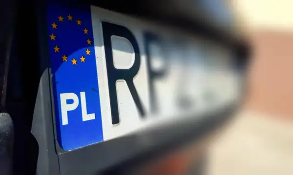 Zbliżenie na polską tablicę rejestracyjną z symbolem Unii Europejskiej. Litery "PL" i fragment numeru wskazują na rkl rejestracja.