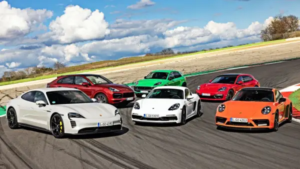 Kolekcja sportowych modeli Porsche: biały Taycan, czerwony Cayenne, zielony Macan, biały Cayman, czerwona Panamera Sport Turismo i pomarańczowy 911 na torze wyścigowym.