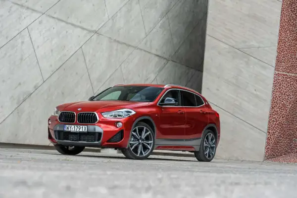 Czerwone BMW X2 na tle nowoczesnej architektury. Wiele osób szuka bmw x2 opinie przed zakupem.